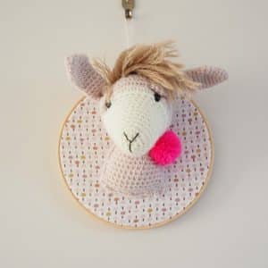 Trophée en crochet. Lama beige et écru. Pompon rose fluo. Monté sur un tambour.