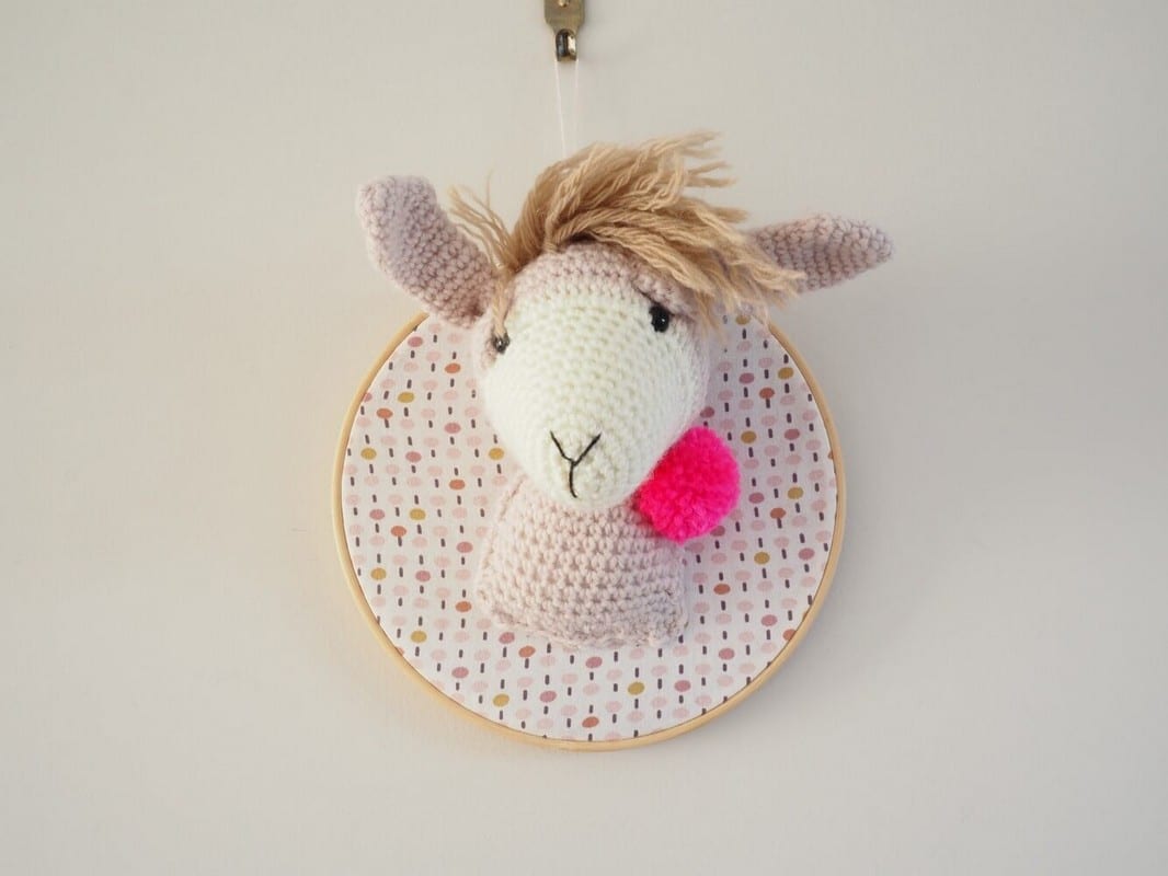 Trophée en crochet. Lama beige et écru. Pompon rose fluo. Monté sur un tambour.