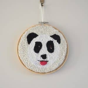 Décoration murale. Cadre réalisé à la punchneedle représentant un panda tirant la langue. La langue est réalisée au crochet.