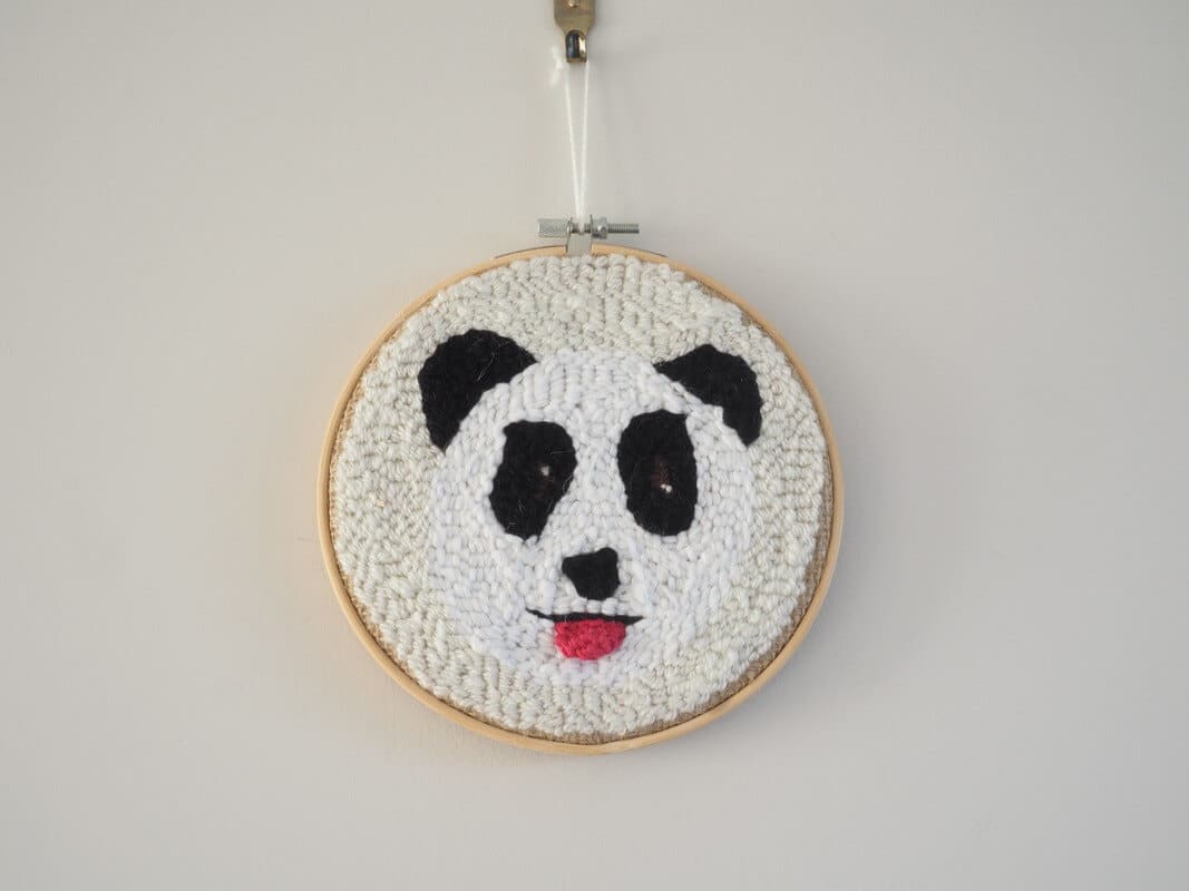 Décoration murale. Cadre réalisé à la punchneedle représentant un panda tirant la langue. La langue est réalisée au crochet.