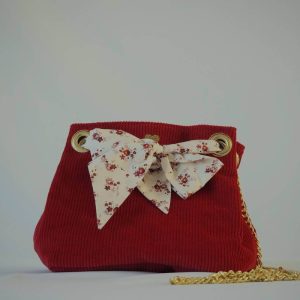 Sac seau en velours rouge porté croisé par une chaine dorée. Fermeture par un bandeau en tissu coton écru, petites fleurs rouges vintage.