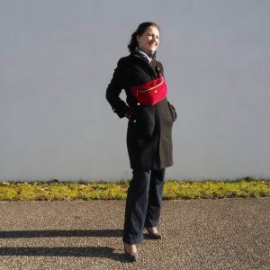 Sac banane Fanny, en velours côtelé rouge, porté une sur un manteau noir, permettant de réhausser une tenue