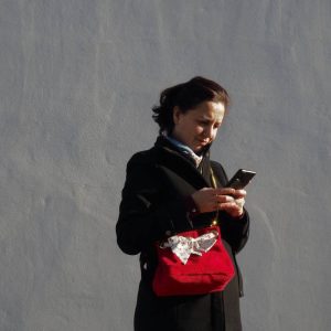 Sac seau en velours rouge avec lien en tissu et chaine dorée porté sur un manteau noir