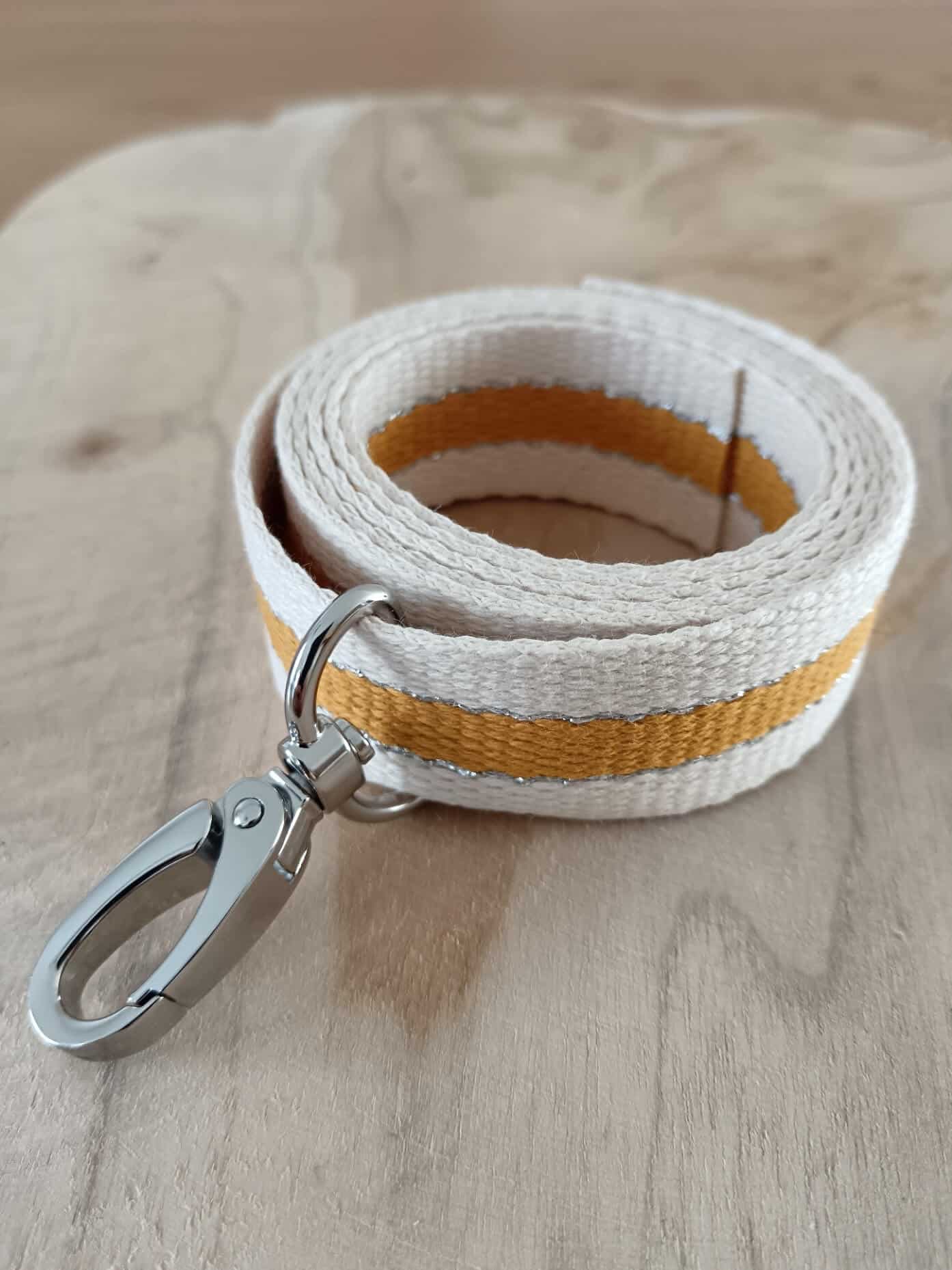 Bandoulières, anses réglables. Coloris : beige, moutarde, liserés argentées Bouclerie argentée.