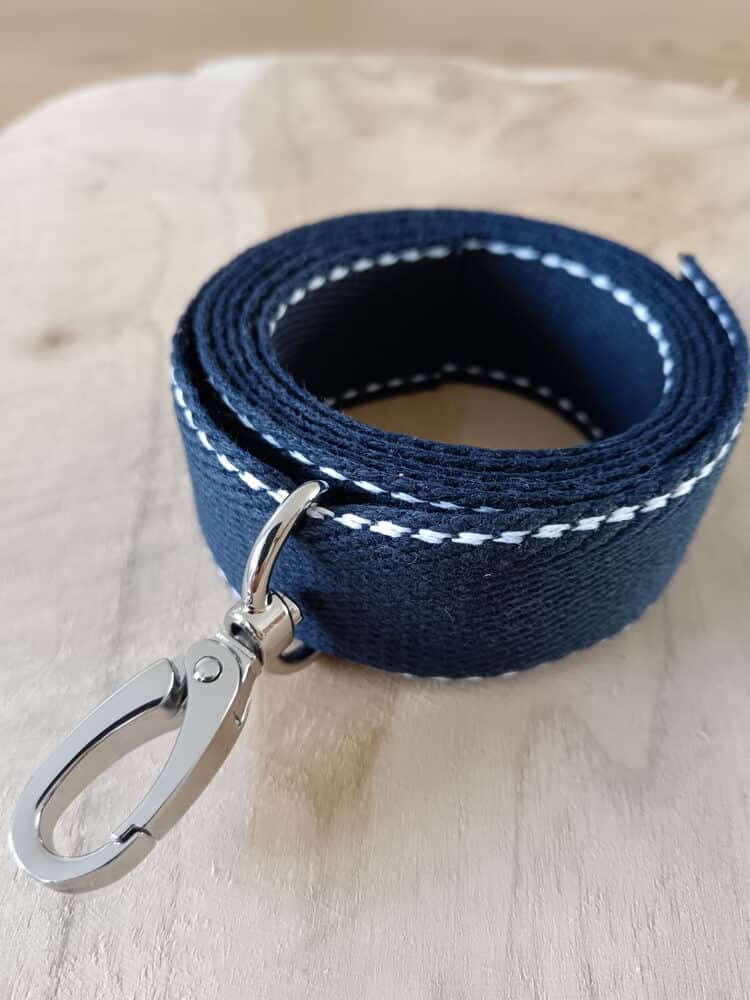 Bandoulières, anses réglables. Coloris : bleu marine, liserés blancs Bouclerie argentée.