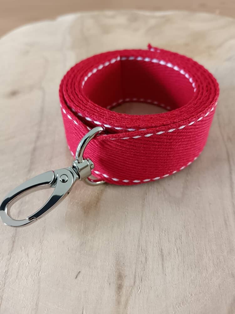 Bandoulières, anses réglables. Coloris : rouge, liserés blancs Bouclerie argentée.