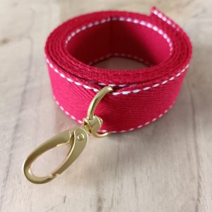 Bandoulières, anses réglables. Coloris : rouge, liserés blancs Bouclerie dorée.
