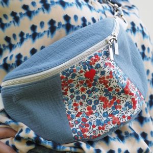 Sac banane bleu avec empiècement en liberty bleu et rouge avec bandoulière interchangeable porté sur une blouse bleue et blanche