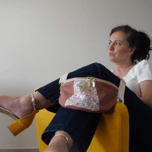 Sac banane en gabardine de couleur sienne avec un empiècement central fleuri. Le sac banane est tenu.