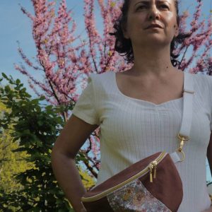 Sac banane en gabardine de couleur sienne avec un empiècement central fleuri. Le sac banane est porté en cross body sur un haut blanc et un pantalon en jean.