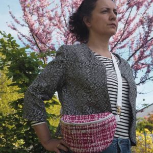 Banane élégante en tweed de couleur fuchsia portée sur une veste coute en jacquard noir et blanc et un pantalon jean.