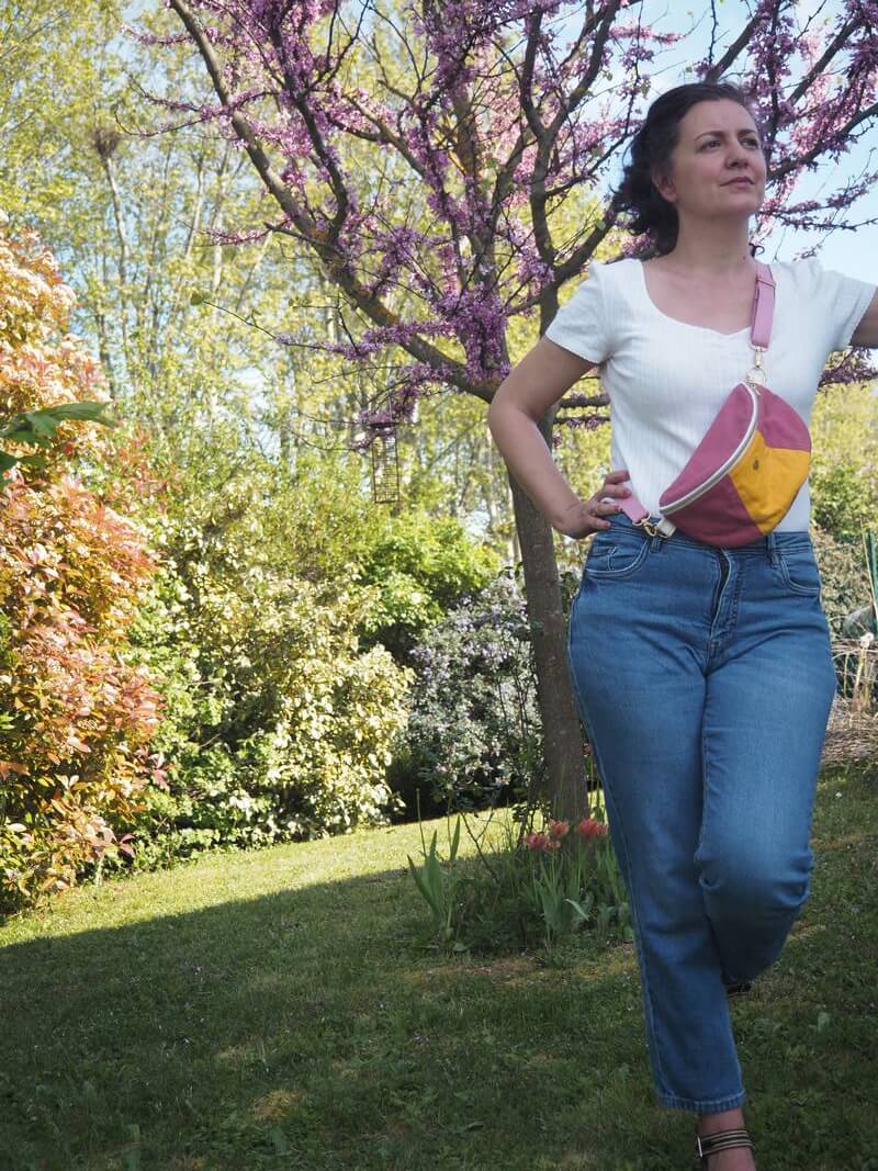 Sac banane 90's rose avec empiècement jaune porté sur un jean et haut blanc