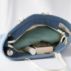 Sac cabas en double gaze de couleur bleu orage, avec fermeture par zip contenant des affaires de plage