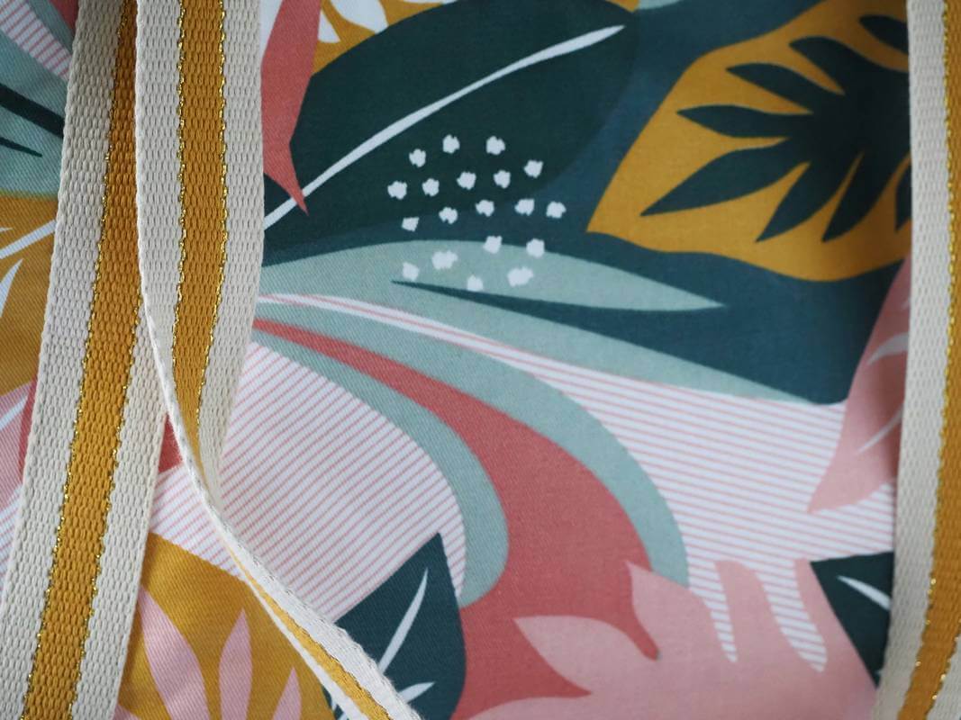 Sac cabas en coton enduit, de motif tropical multicolor (rose, vert, moutarde,...) , avec fermeture par zip. Détail de la anse.