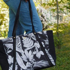 Sac cabas noir à motif tropical porté à bout de bras