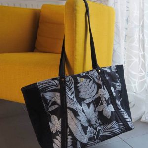 Sac cabas noir à motif tropical posé sur un fauteuil.